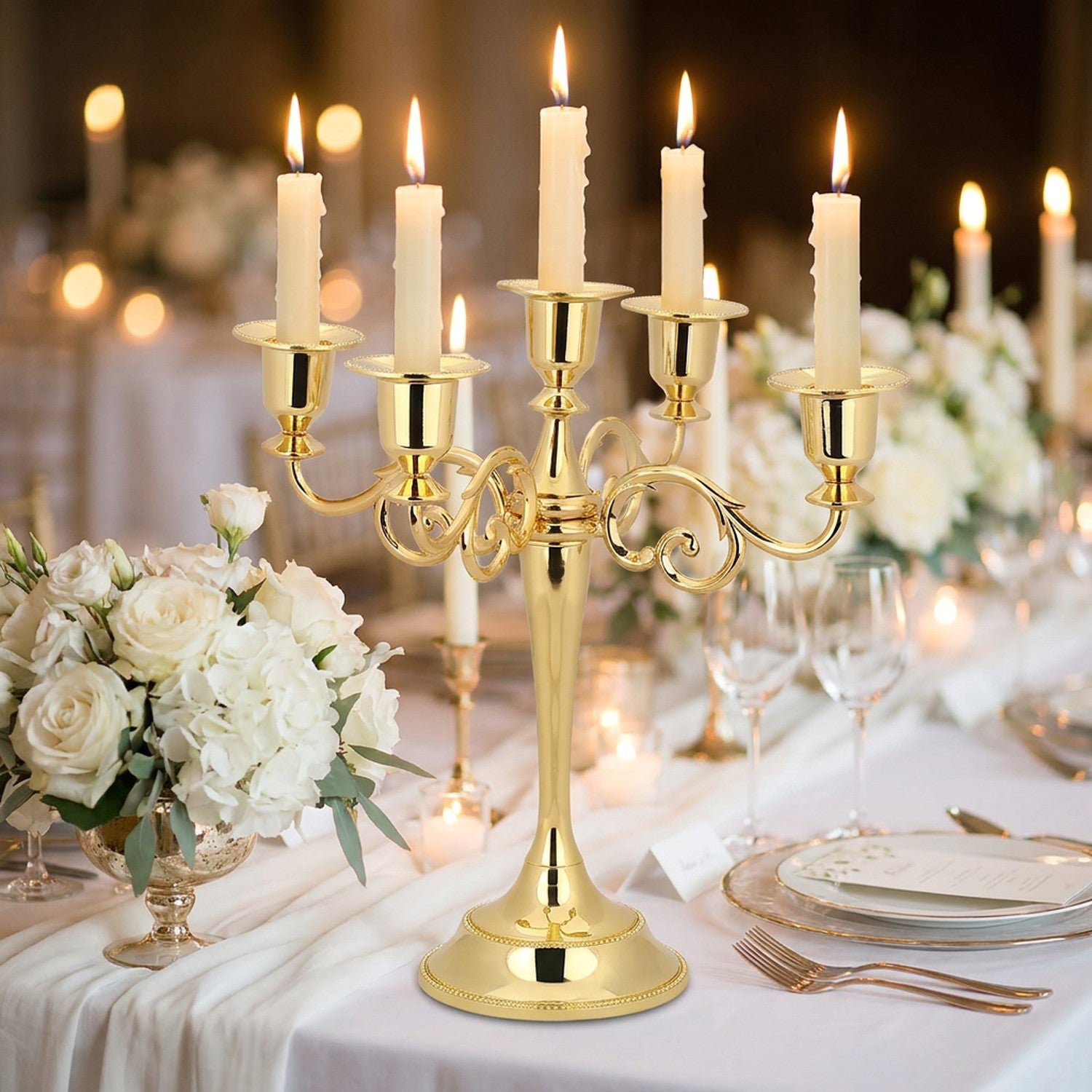 Chandelier doré à 5 branches sur une table de mariage fleurie avec bougies allumées