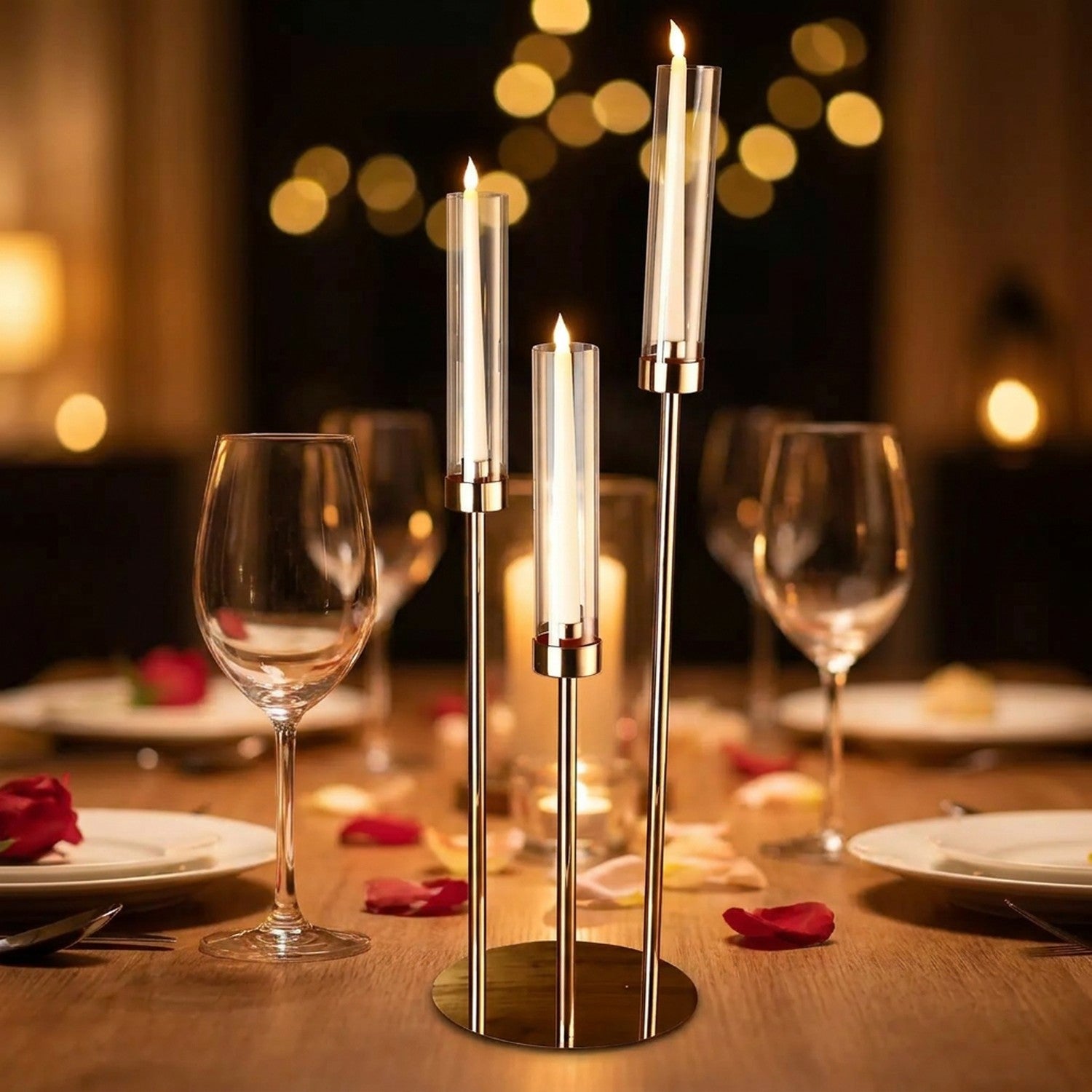 Chandelier doré à 3 branches avec bougies LED allumées dans des verres cylindriques posé sur une table dressée