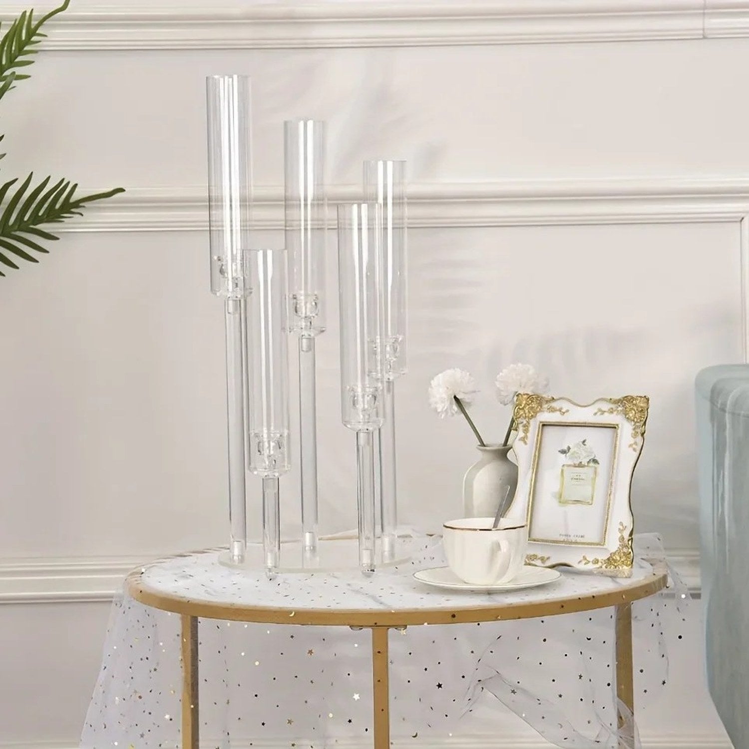 Chandelier acrylique transparent 5 bras posé sur une table décorée avec nappe dorée