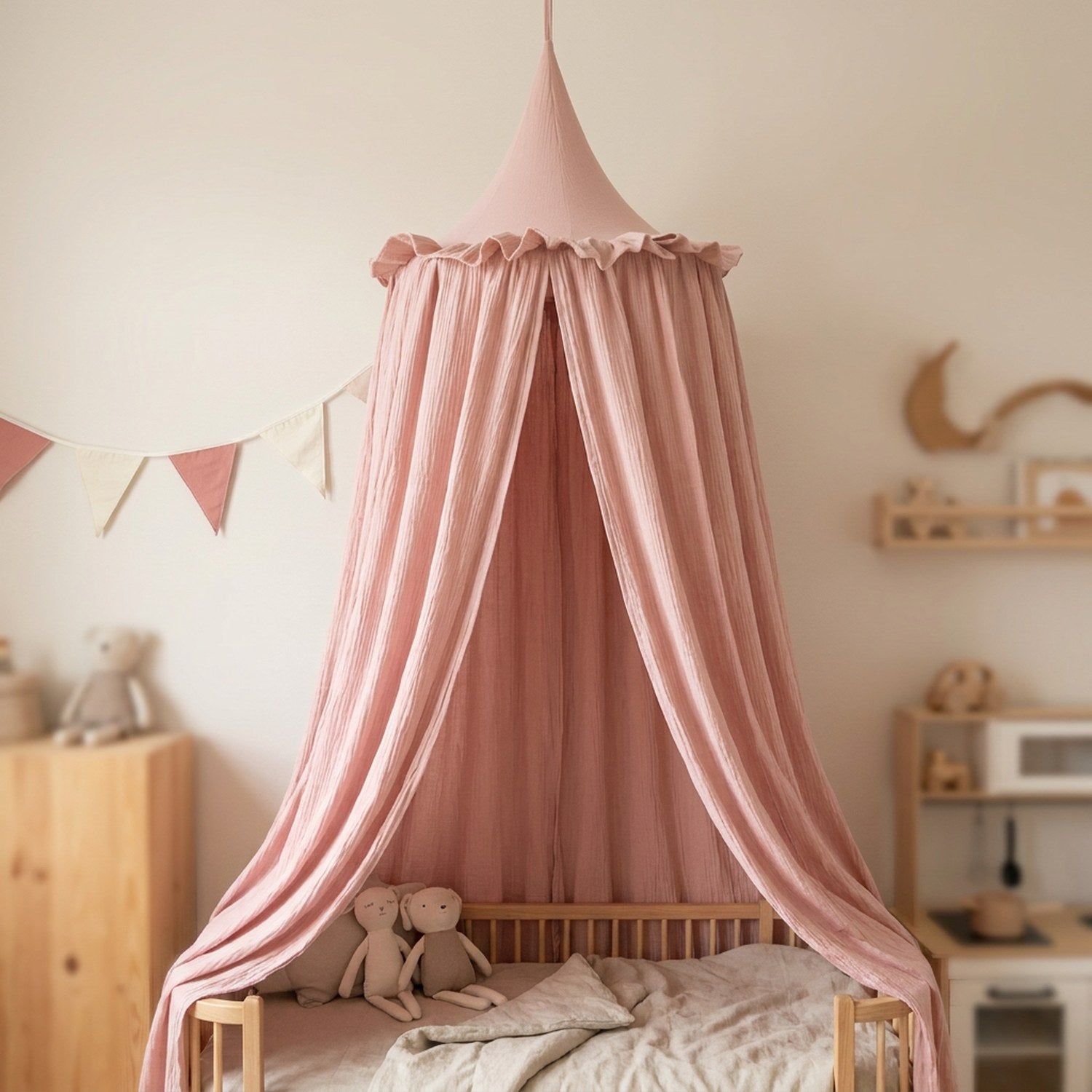 Ciel de lit rose en mousseline de coton au-dessus d'un lit bebe dans une chambre douce