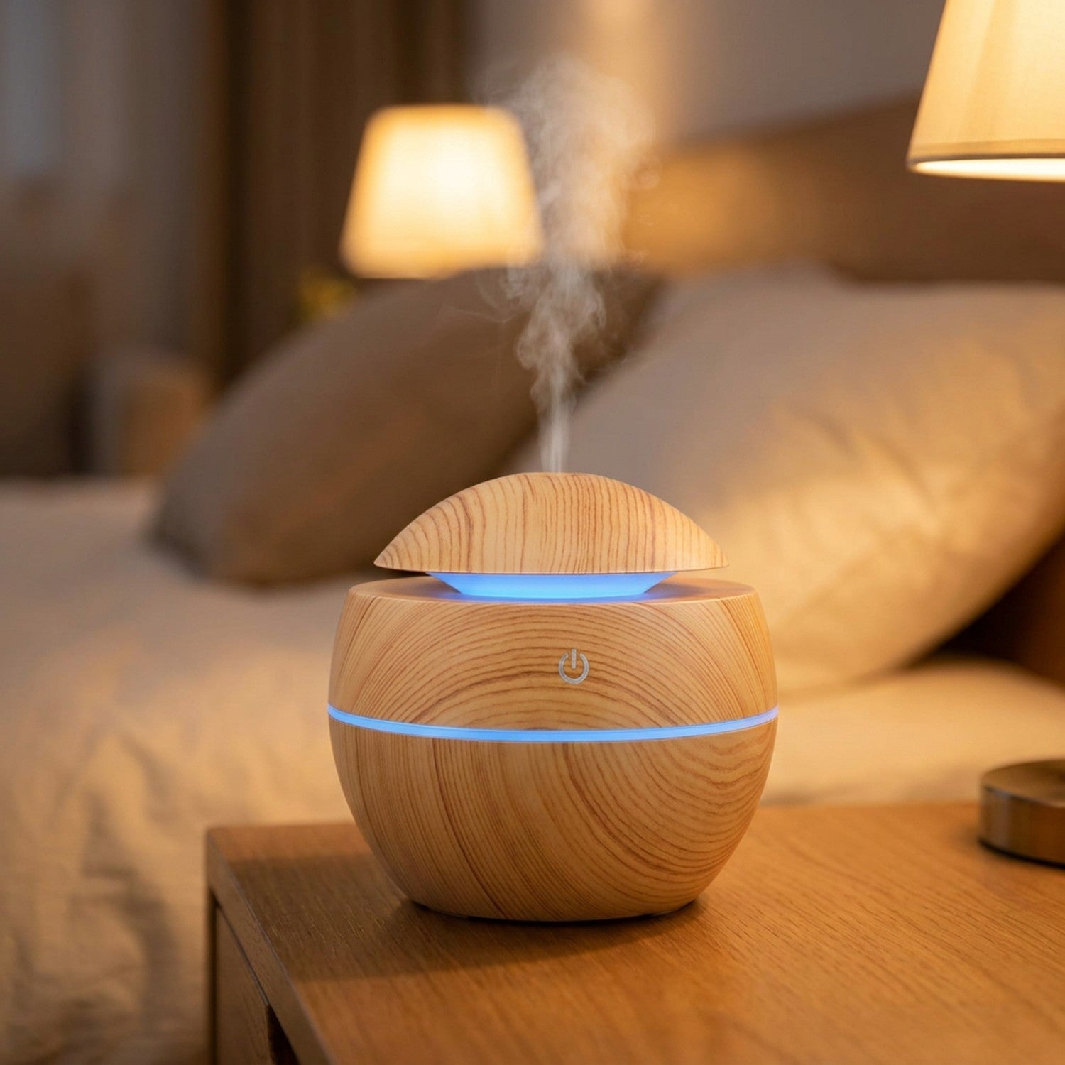 Diffuseur d'huiles essentielles à ultrasons effet bois clair diffusant une brume sur une table de chevet