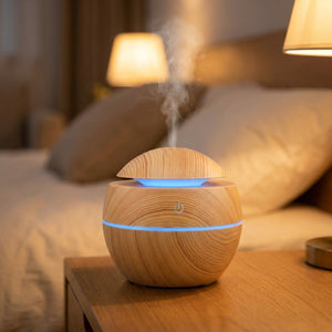Diffuseur d'huiles essentielles à ultrasons effet bois clair diffusant une brume sur une table de chevet