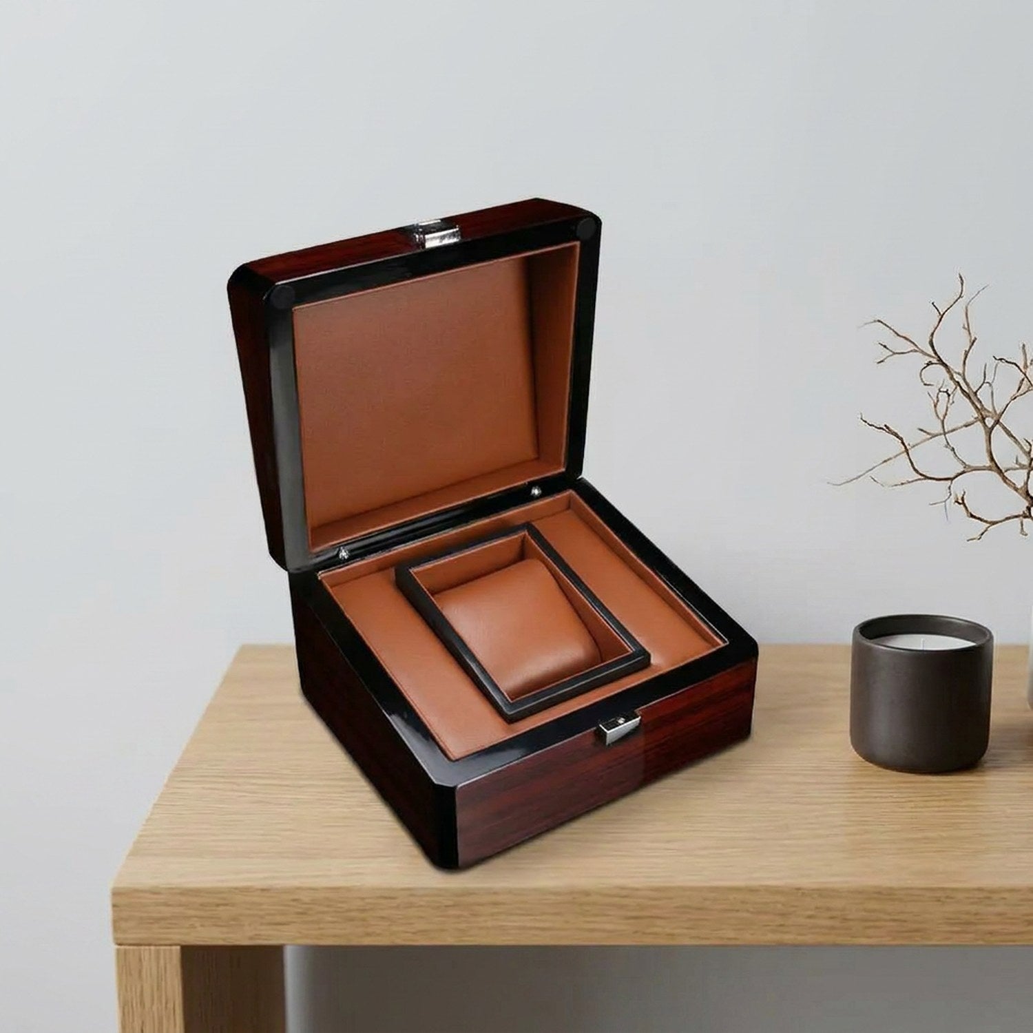 Coffret montre ouvert vue de dessus sur étagère bois avec bougeoir et branche décorative