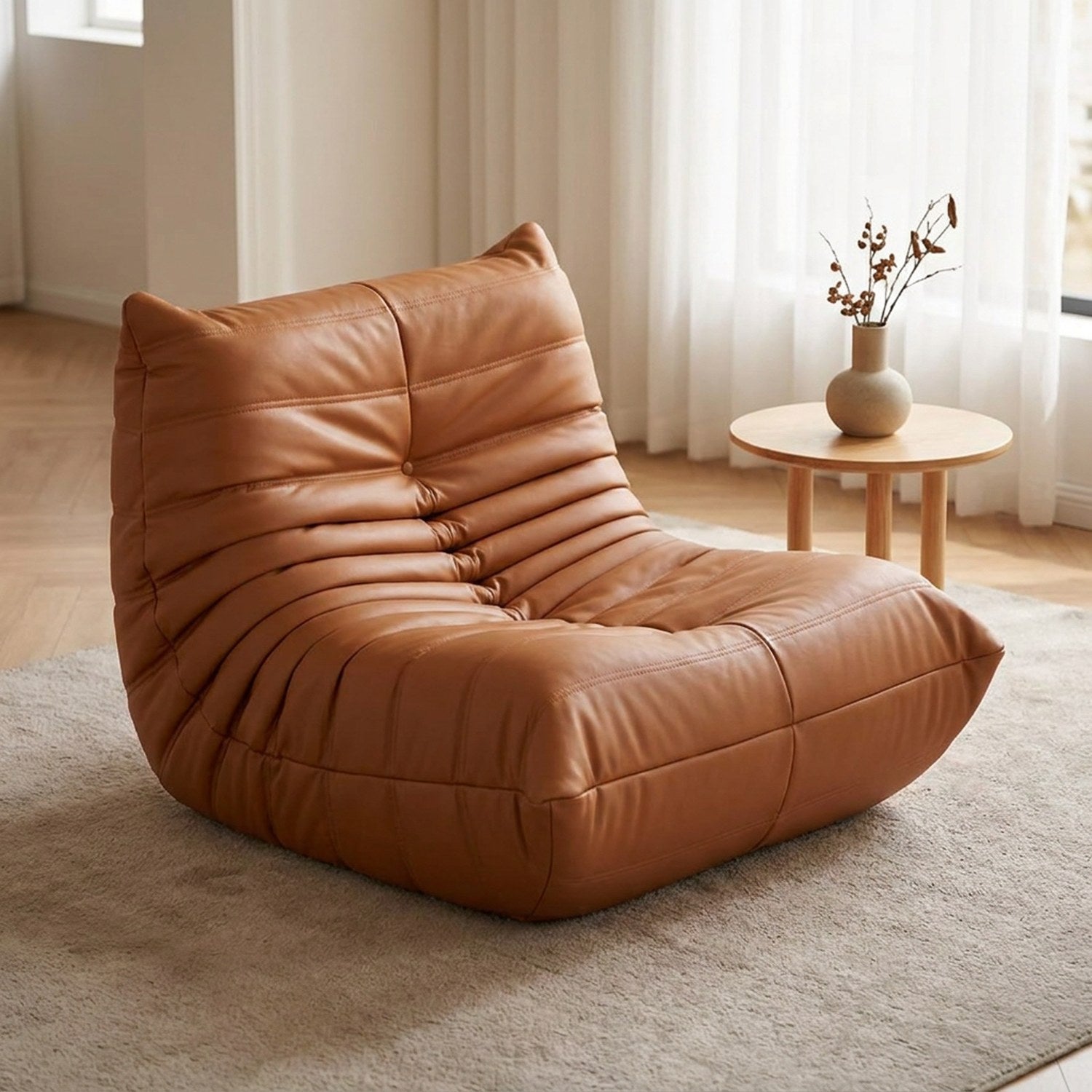 Pouf géant canapé de sol matelassé en simili cuir cognac posé dans un salon lumineux et chaleureux