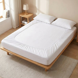 drap-housse en coton blanc posé sur un lit dans une chambre lumineuse