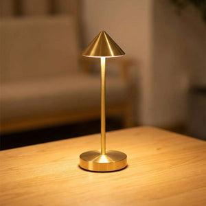 Lampe de table sans fil dorée allumée sur une table en bois chaleureuse