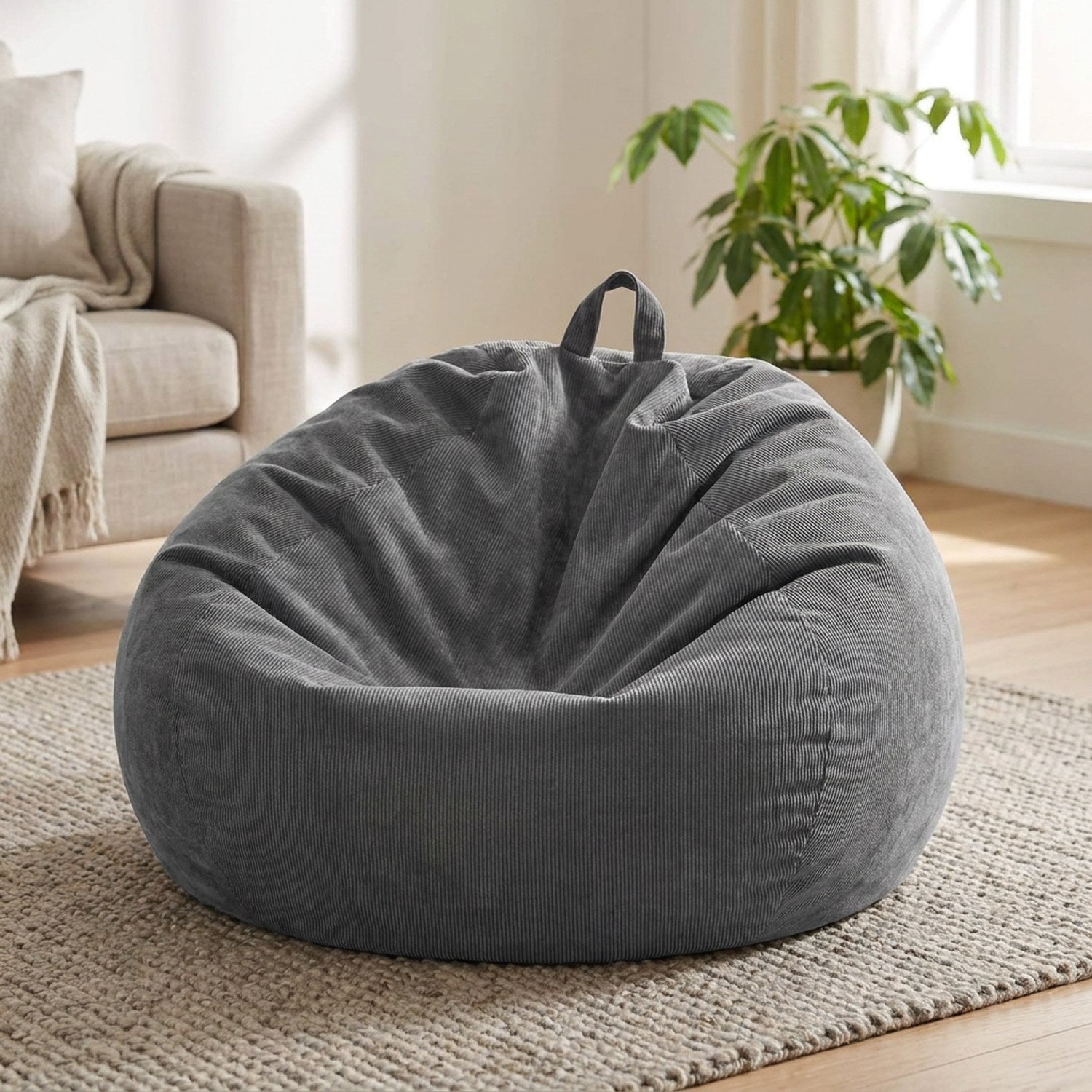 Housse de pouf poire en velours côtelé gris posée au sol dans un salon