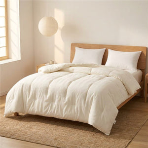 Couette matelassée blanche installée sur un lit fait dans une chambre minimaliste lumineuse