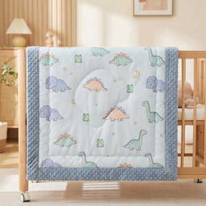 Couette bébé motif dinosaures avec bordure bleue à pois dans un berceau