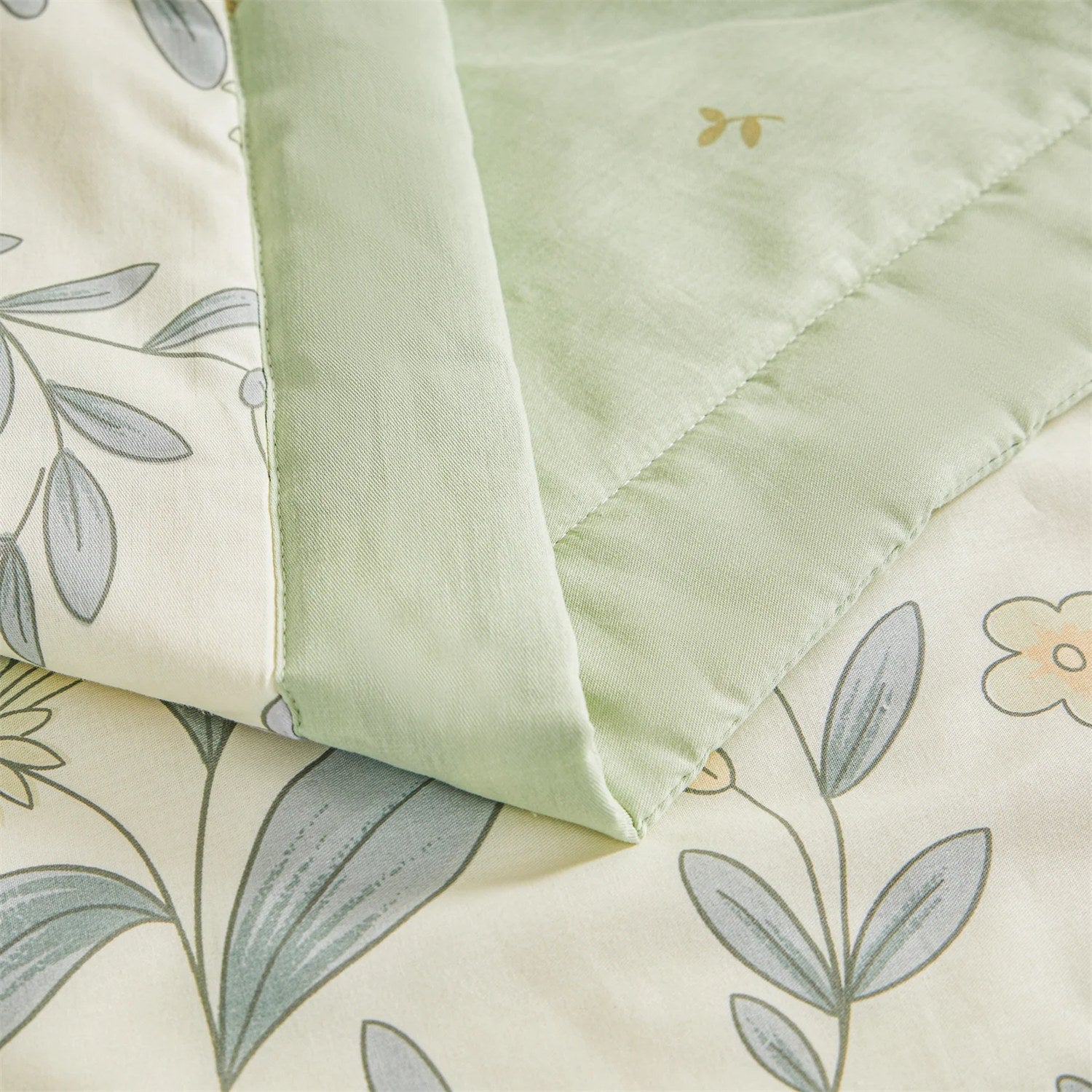 Détail de la bordure vert sauge et de la broderie sur la couette d'été