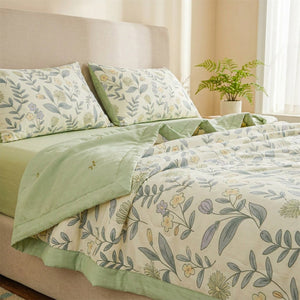 Couette d'été légère imprimé floral vert sauge posée sur un lit dans une chambre lumineuse