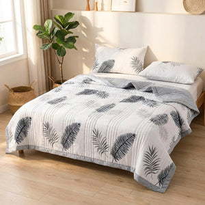 Couette d'été feuillage étalée sur un lit dans une chambre minimaliste avec plante verte