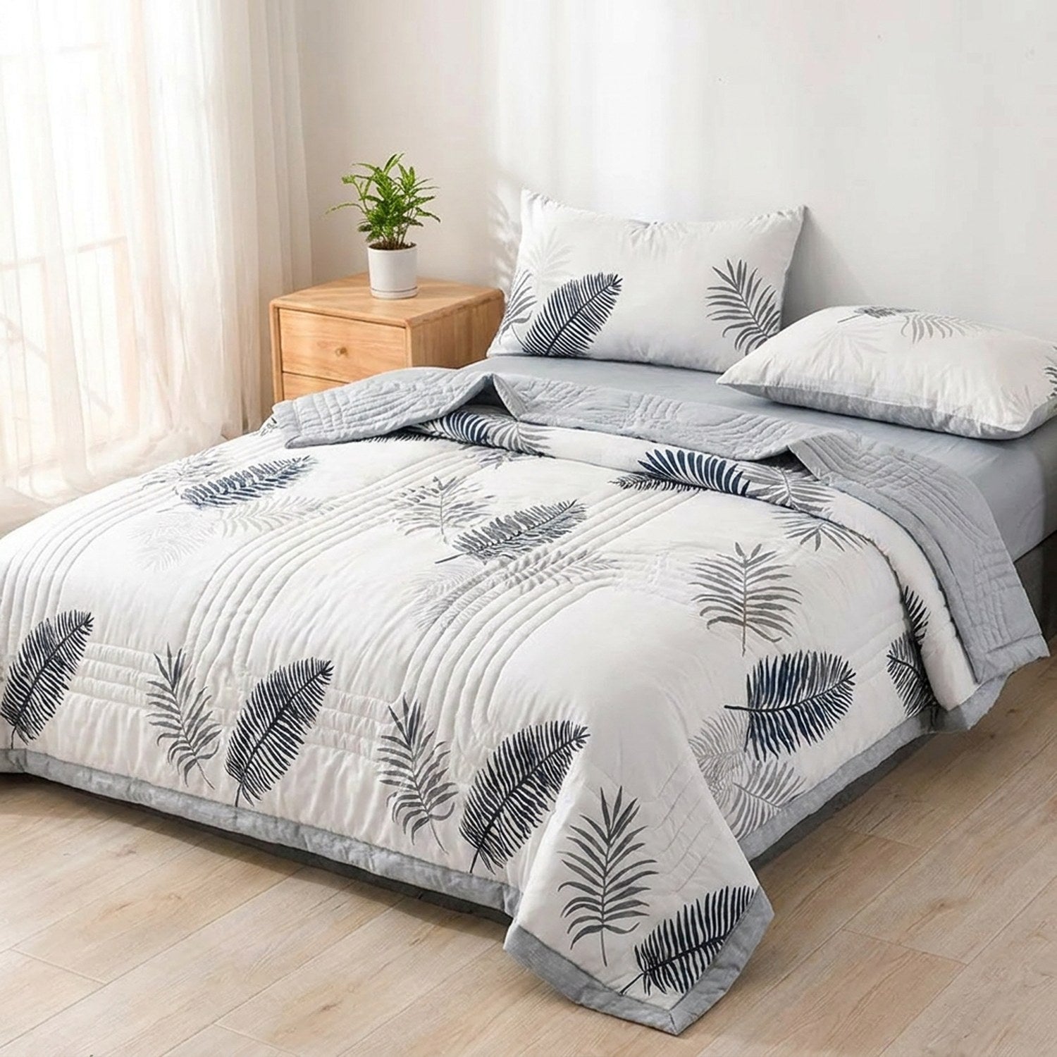 Couette d'été à motif de feuillage bleu marine posée sur un lit fait dans une chambre lumineuse