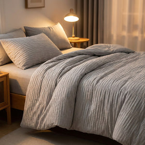 Couette grise en coton seersucker sur un lit avec table de chevet et lampe chaleureuse