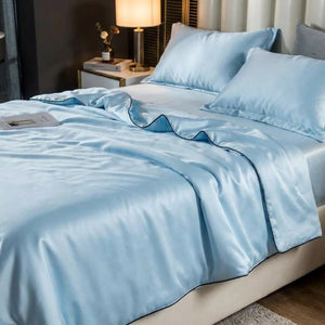 Couette d'été bleu ciel sur un lit avec table de chevet et lampe chaleureuse