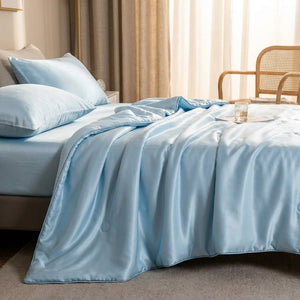 Couette d'été bleu ciel sur un lit dans une chambre lumineuse avec fauteuil en rotin