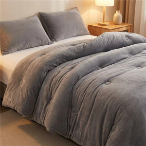 Couette grise en velours de lait matelassée sur un lit dans une chambre cosy