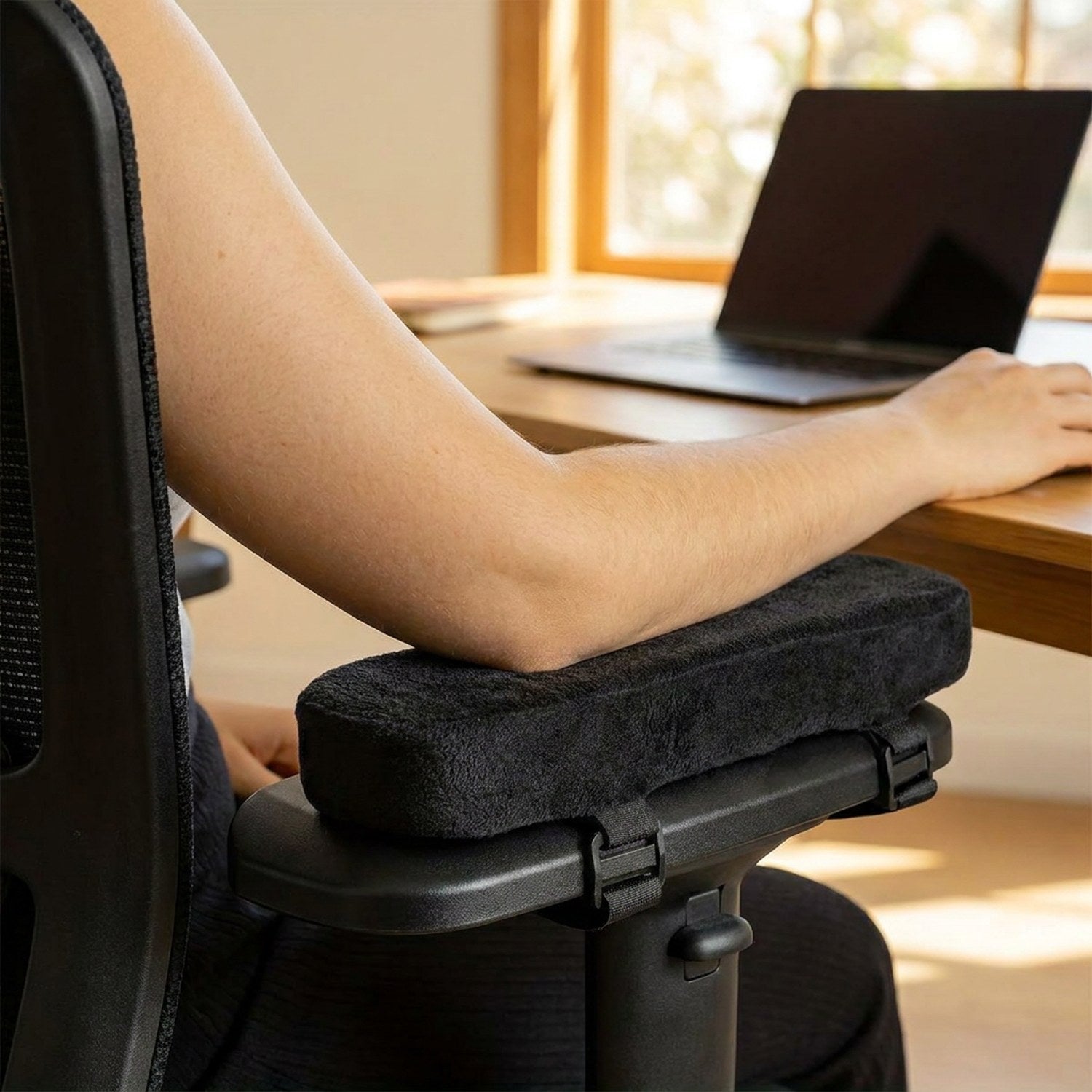 Personne posant son bras sur le coussin d'accoudoir noir installé sur une chaise de bureau