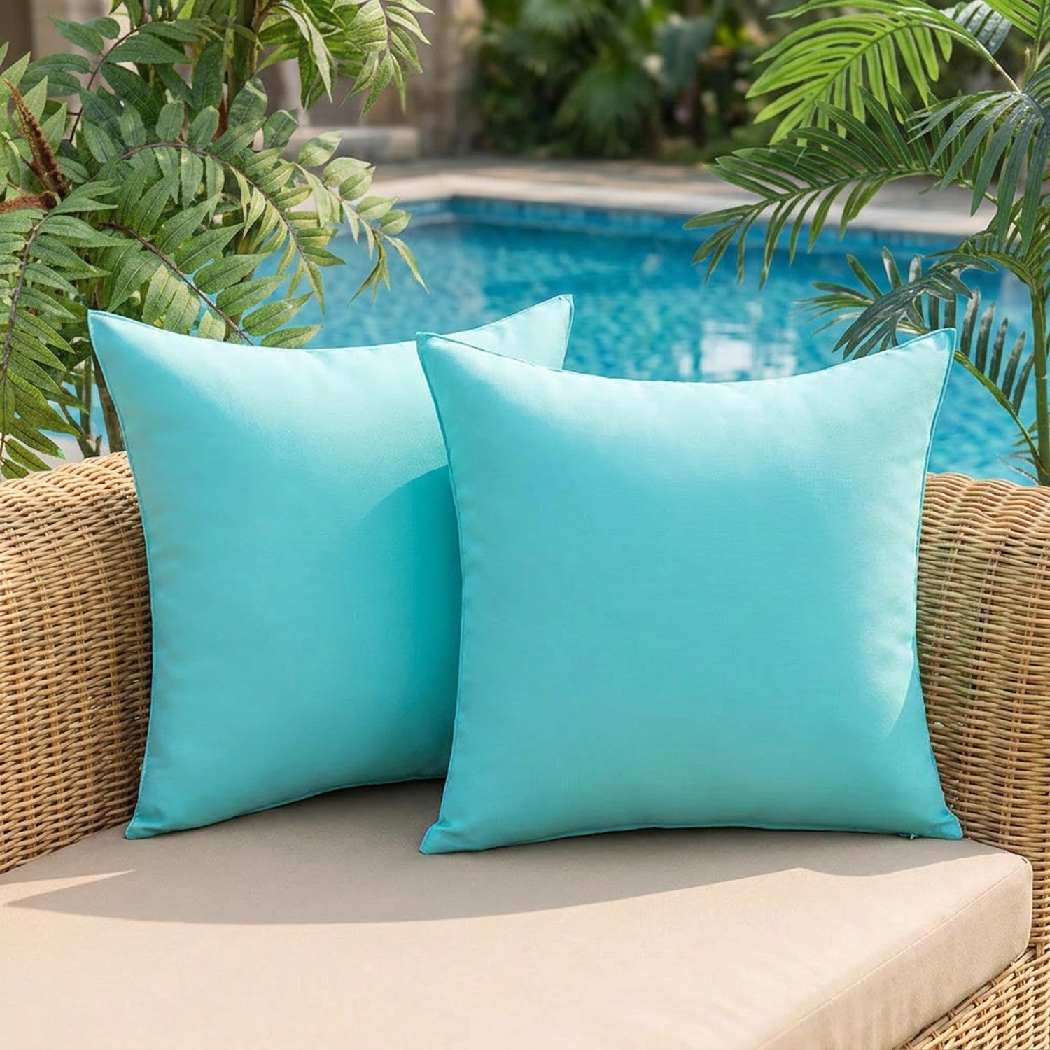 Deux coussins d'extérieur turquoise sur un canapé de jardin au bord d'une piscine
