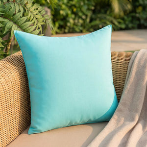 Coussin d'extérieur turquoise imperméable posé sur un fauteuil en résine tressée sur une terrasse