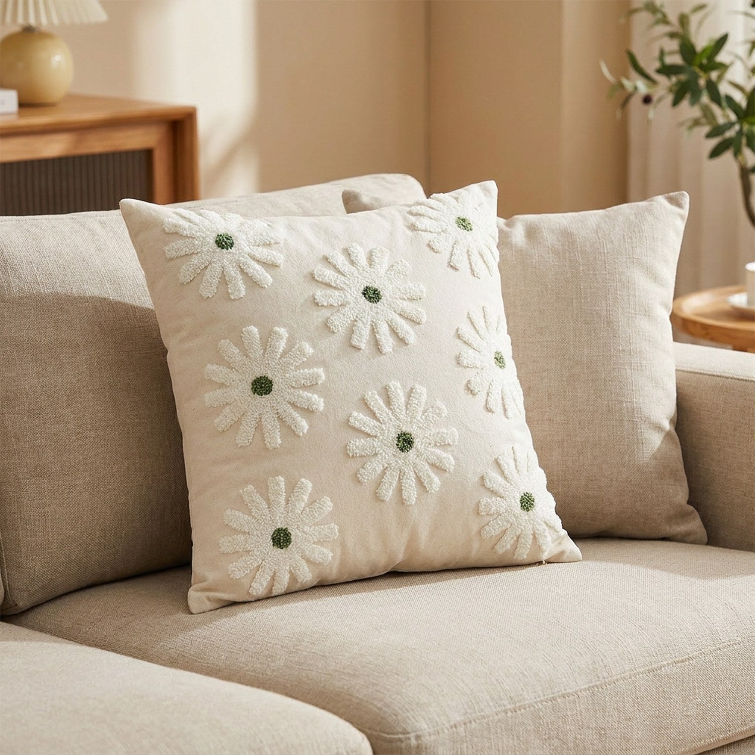 Housse de coussin motif marguerite verte posée sur un canapé