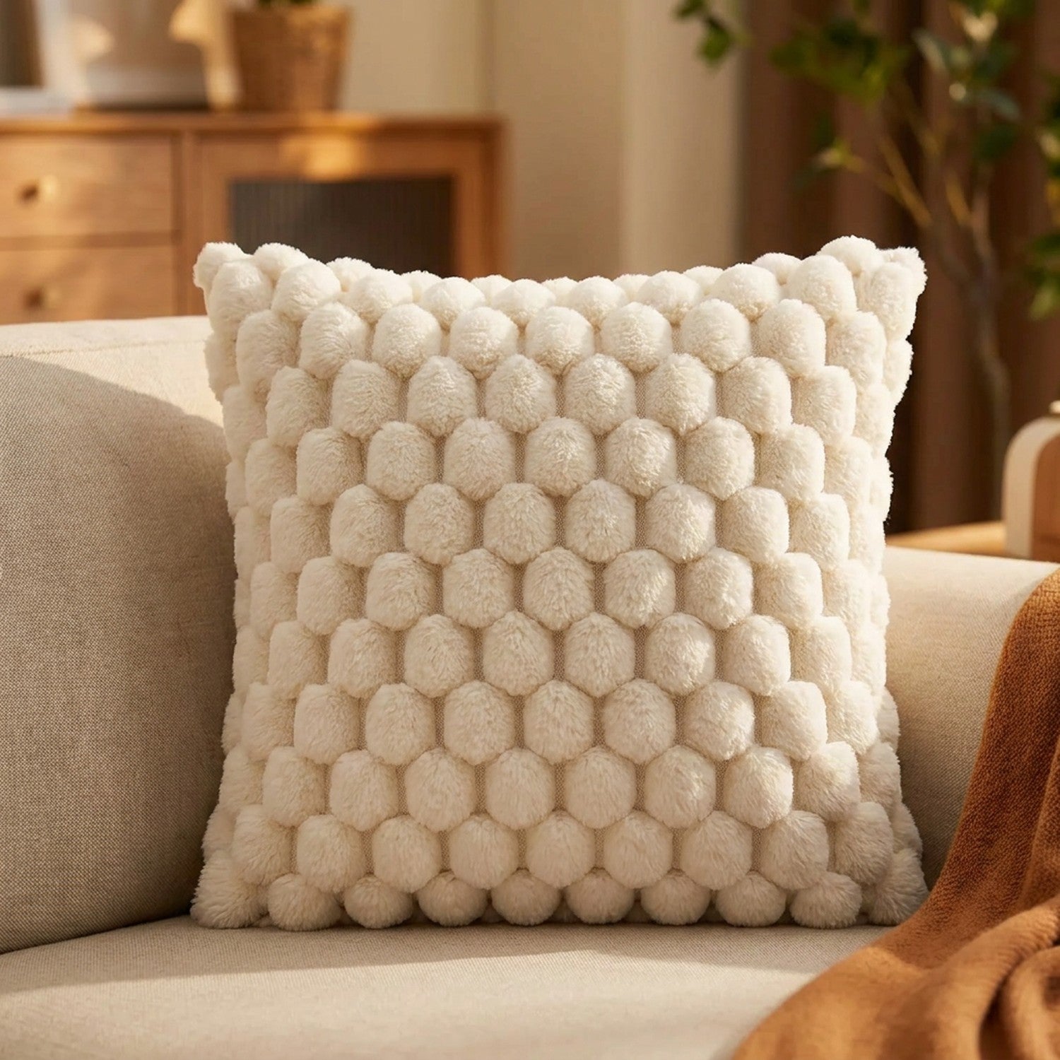 Housse de coussin à pompons de couleur crème sur un canapé
