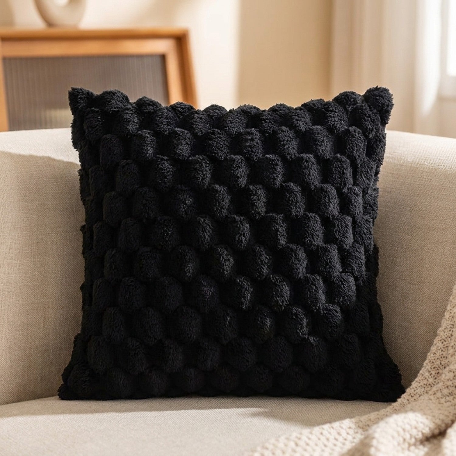 Housse de coussin à pompons de couleur noire sur un canapé