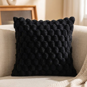 Housse de coussin à pompons de couleur noire sur un canapé