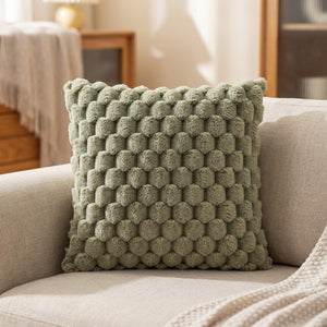 Housse de coussin à pompons de couleur vert sauge sur un canapé