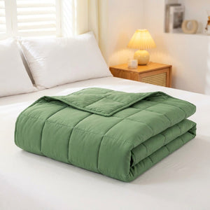 Couverture lestée verte pliée sur un lit