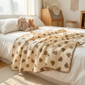 Couverture en gaze de coton étalée sur un lit dans une chambre lumineuse avec peluches