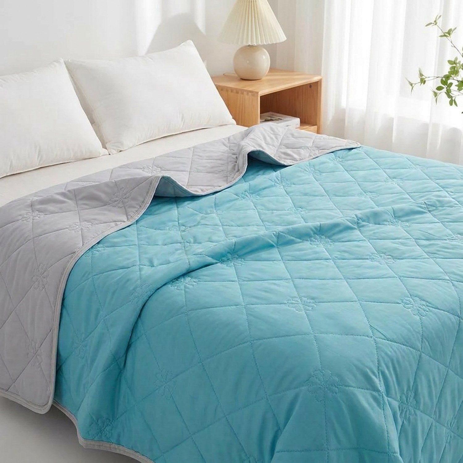Couverture rafraîchissante d'été bleue au matelassage fleur posée sur un lit dans une chambre lumineuse