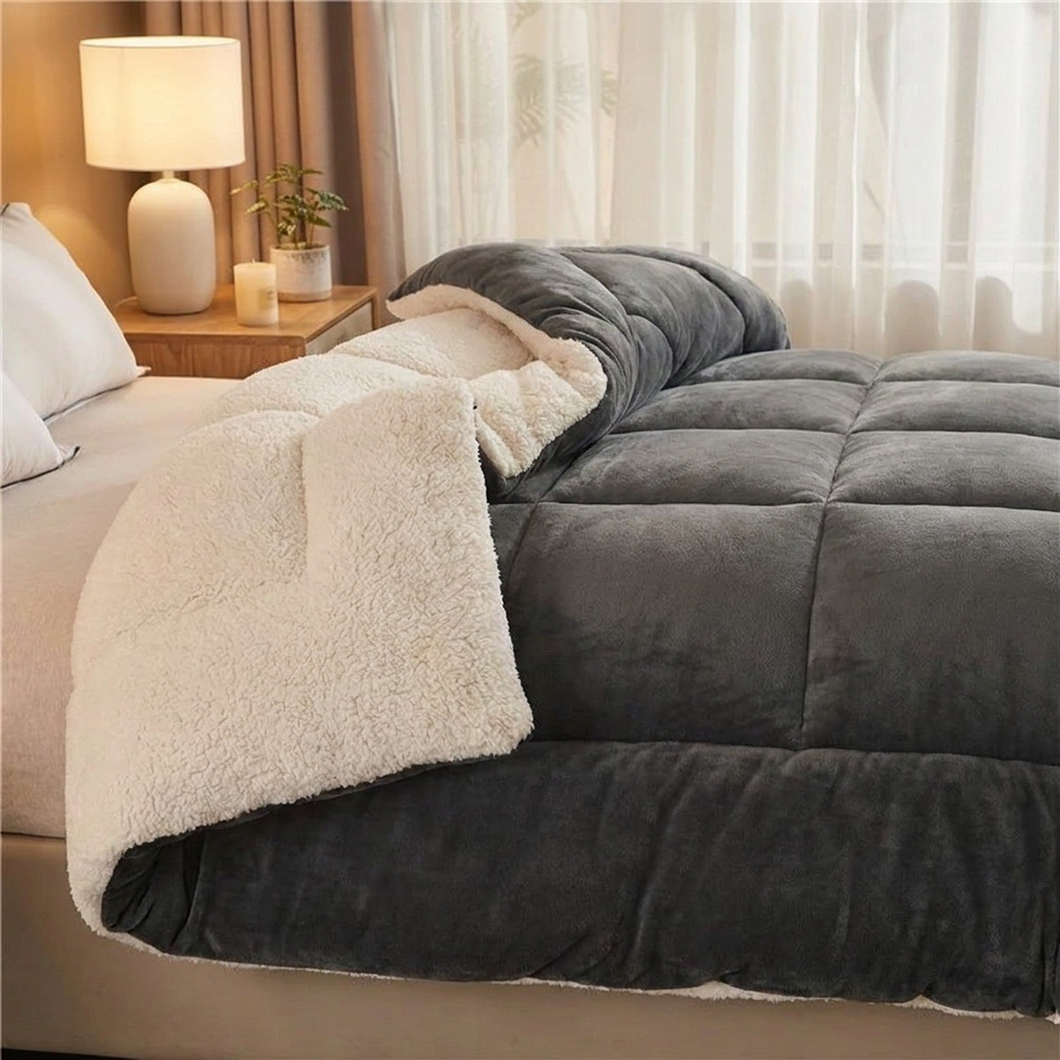 Couverture chaude réversible anthracite en velours et effet mouton sur un lit cosy