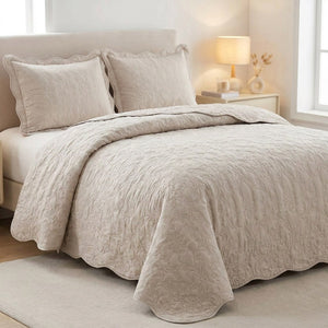 Couvre-lit matelassé beige avec deux taies assorties sur un lit dans une chambre lumineuse