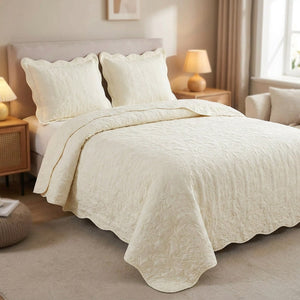 Couvre-lit matelassé blanc cassé avec deux taies assorties sur un lit dans une chambre lumineuse