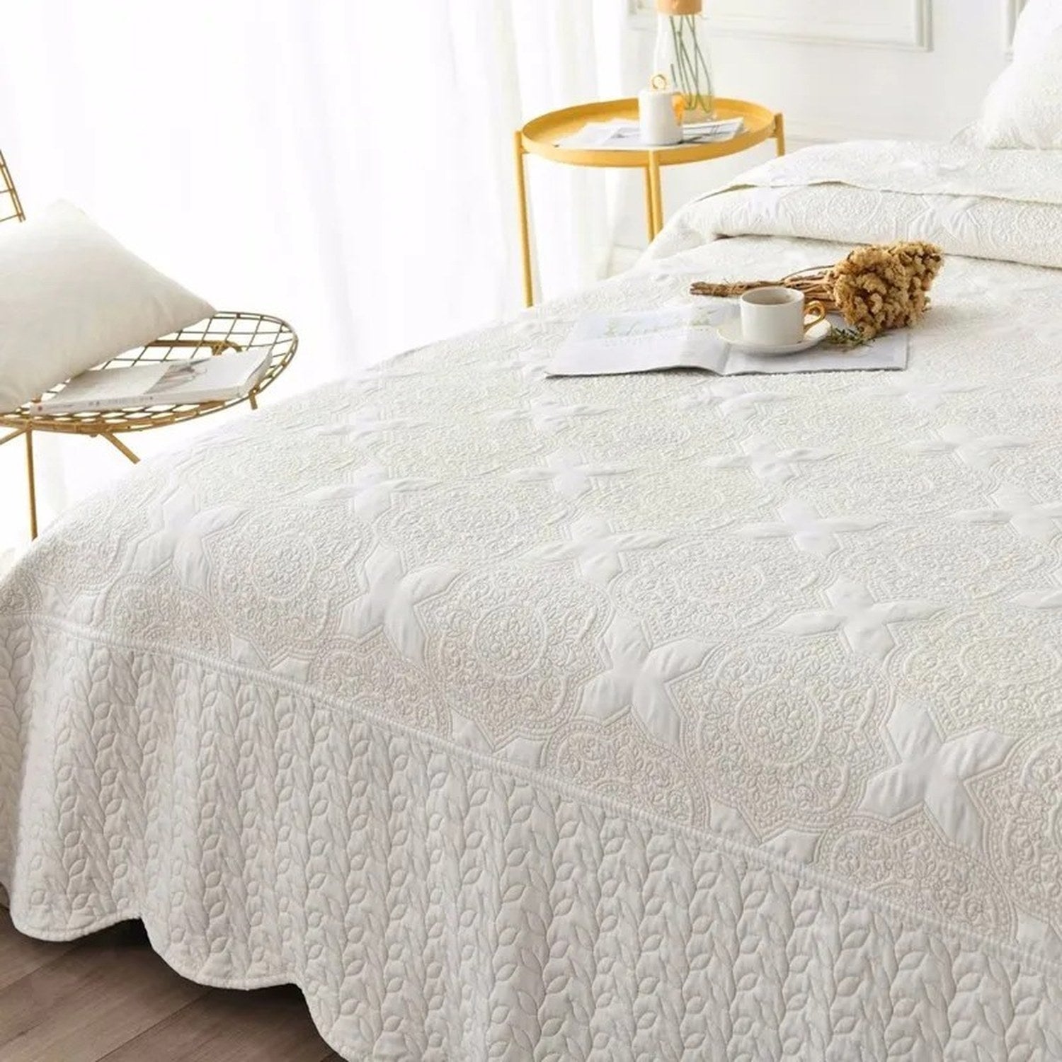 Couvre-lit matelassé blanc vue complète sur un lit avec table d'appoint dorée