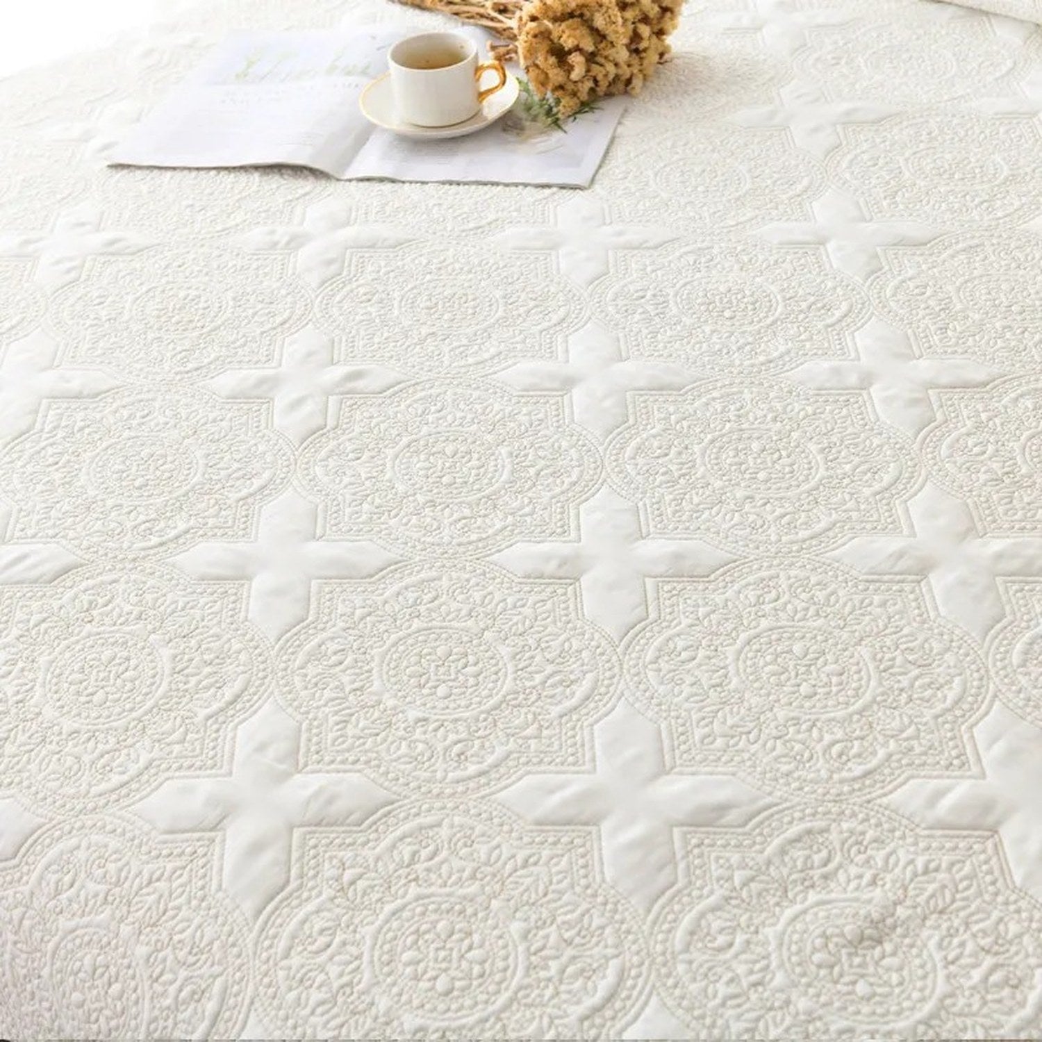 Détail de la broderie florale et du motif médaillon matelassé du couvre-lit