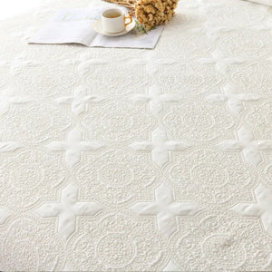 Détail de la broderie florale et du motif médaillon matelassé du couvre-lit