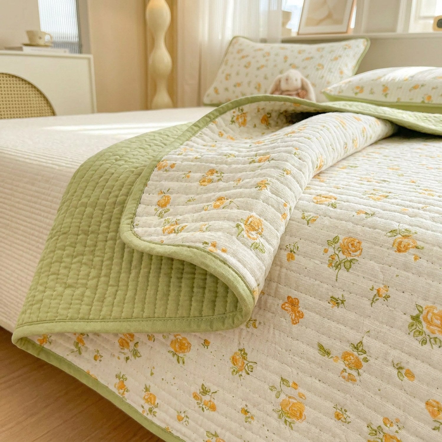Détail du couvre-lit réversible face fleurie et envers vert avec surpiqûres matelassées