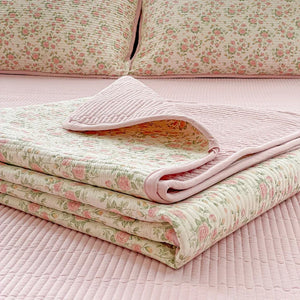 Couvre-lit matelassé imprimé floral rose plié montrant l'envers rose et le motif fleuri