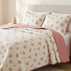 Couvre-lit matelassé imprimé floral rose posé sur un lit dans une chambre lumineuse