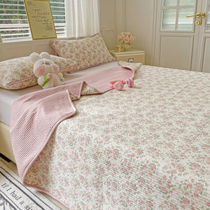 Couvre-lit matelassé imprimé floral rose avec taies d'oreiller assorties sur un lit deux personnes