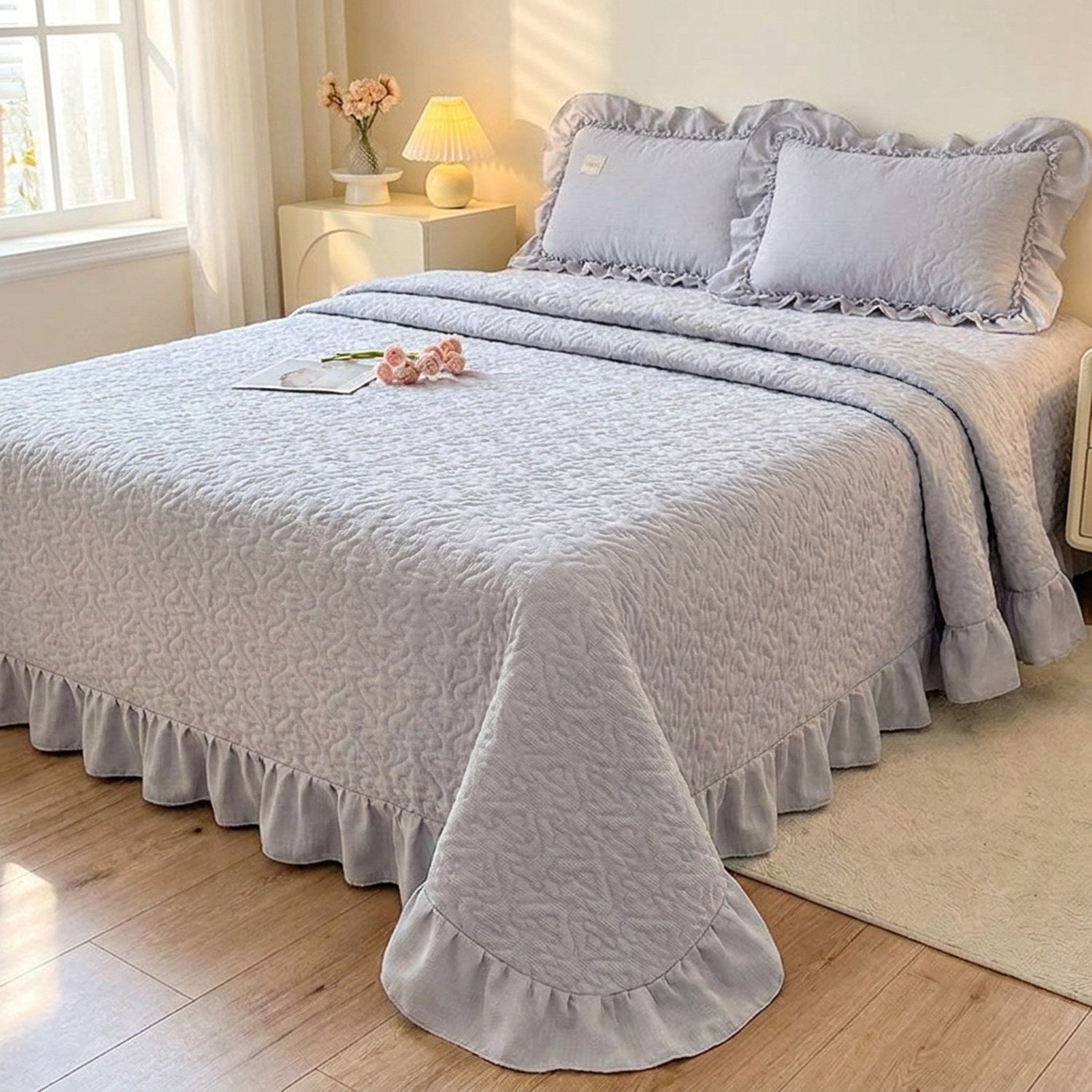 Couvre-lit matelassé gris à motif de cœurs et volant sur un lit