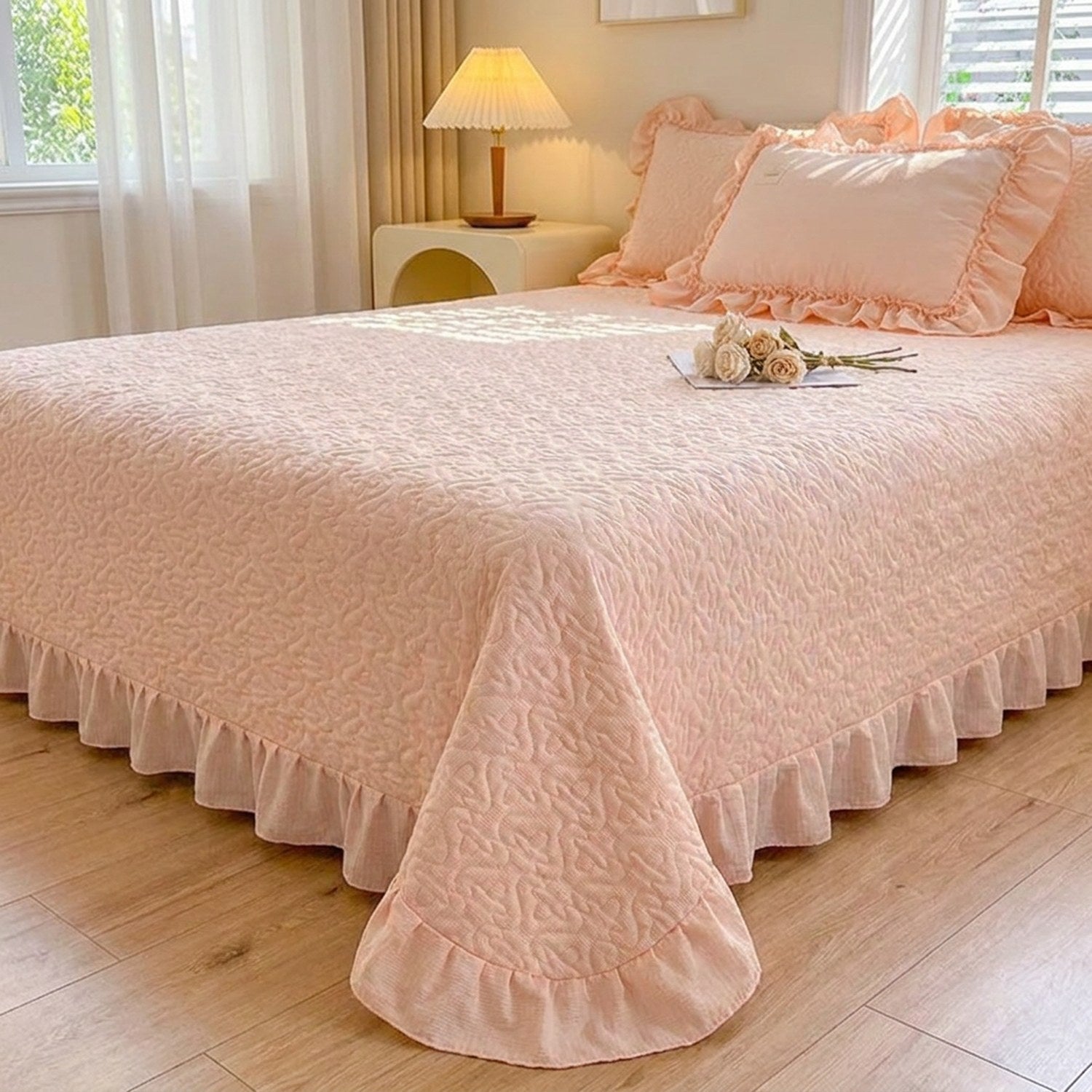 Couvre-lit matelassé rose à motif de cœurs et volant sur un lit