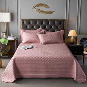Couvre-lit matelassé vieux rose avec deux taies assorties sur un lit