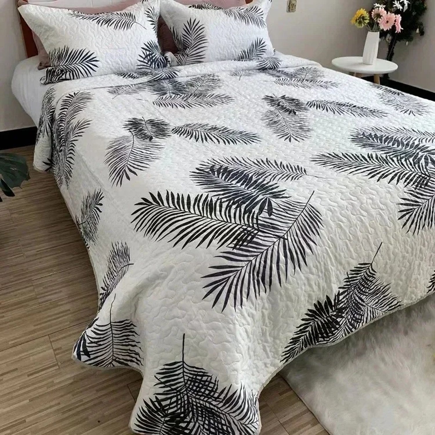 Couvre-lit matelassé blanc à palmes noires graphiques sur un lit lumineux