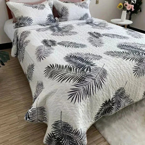 Couvre-lit matelassé blanc à palmes noires graphiques sur un lit lumineux
