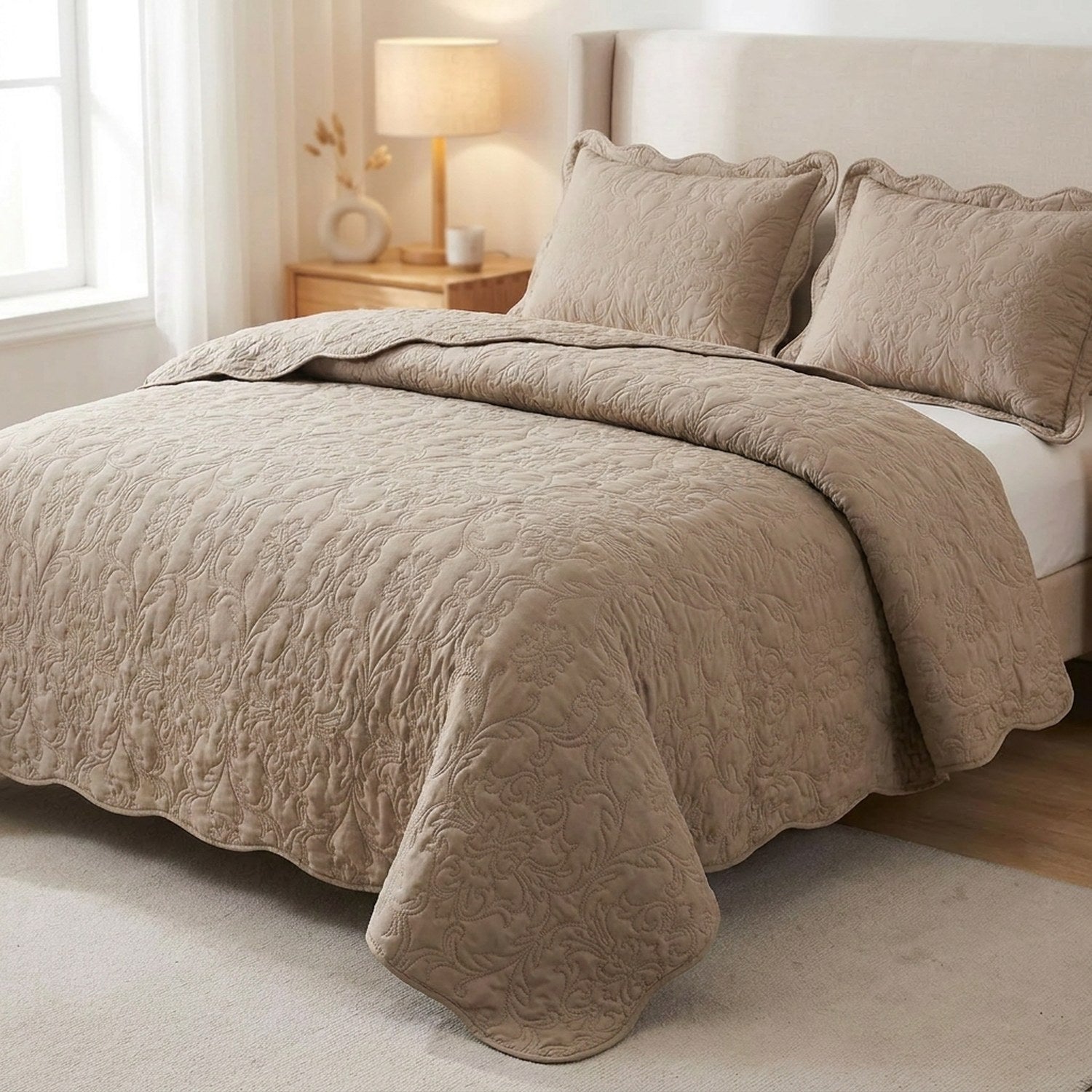 Couvre-lit matelassé taupe au motif baroque en relief installé sur un lit dans une chambre chaleureuse avec deux taies assorties