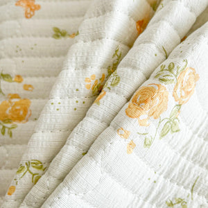 Gros plan sur le tissu matelassé du couvre-lit à petites roses jaunes
