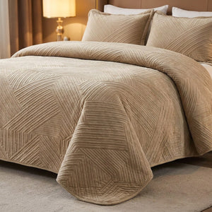 Couvre-lit matelassé velours beige drapé sur un lit avec lampe de chevet dorée